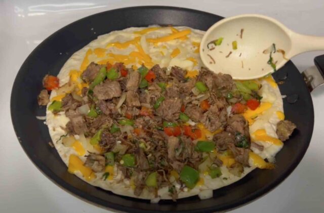 Adding meat to a cheesy tortilla